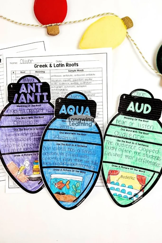 Flatlay of completed Christmas Greek and Latin roots activity ornaments alongside printable worksheets and holiday decor.